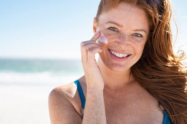 Mature Woman Applying Sunscreen On Face