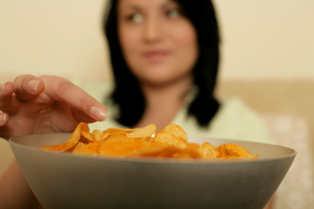 Vrouw eet 's avonds laat chips
