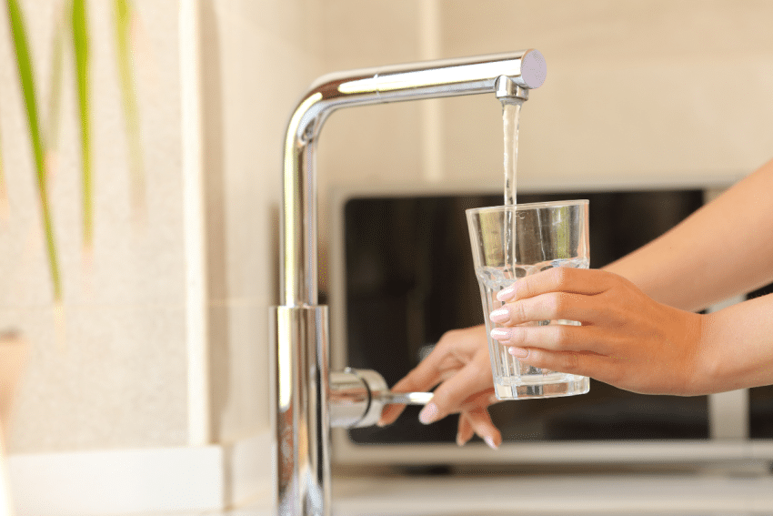 Vrouw vult glas met kraanwater