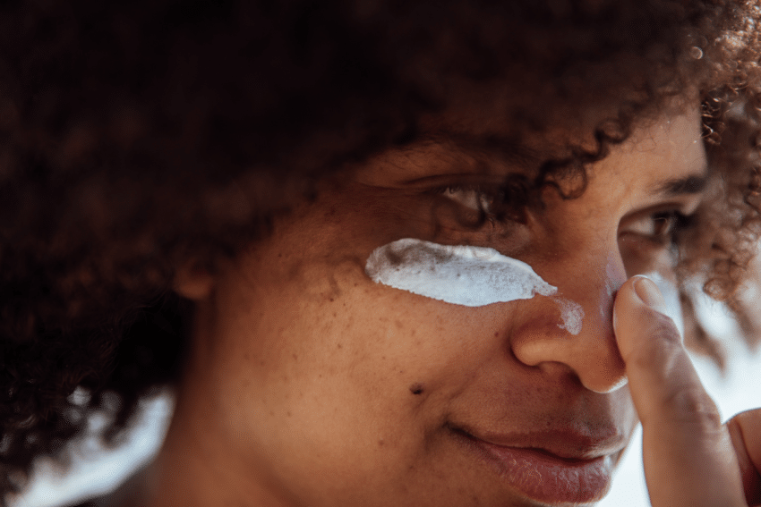 Vrouw doet zonnebrand op haar gezicht