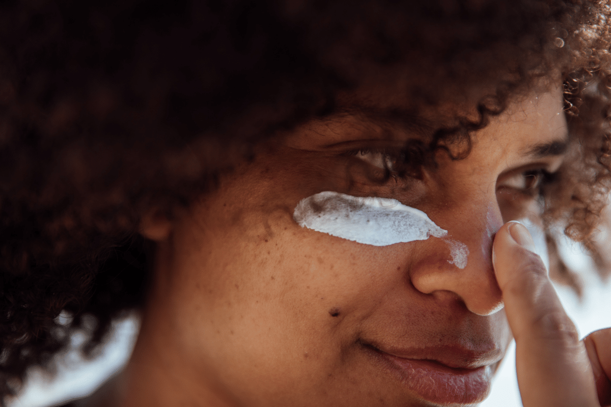 Vrouw doet zonnebrand op haar gezicht