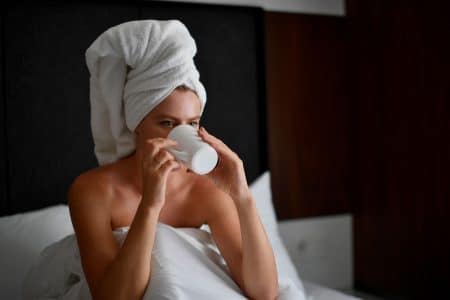 Vrouw Zit Op Bed In Hotel Met Witte Lakens