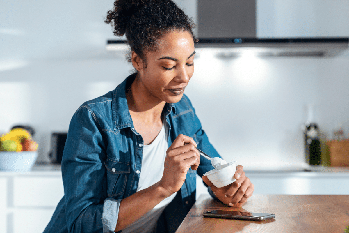 Vrouw eet yoghurt uit een bakje