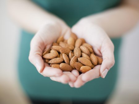 Studio Shot Of Woman Showing Handful Of Almonds